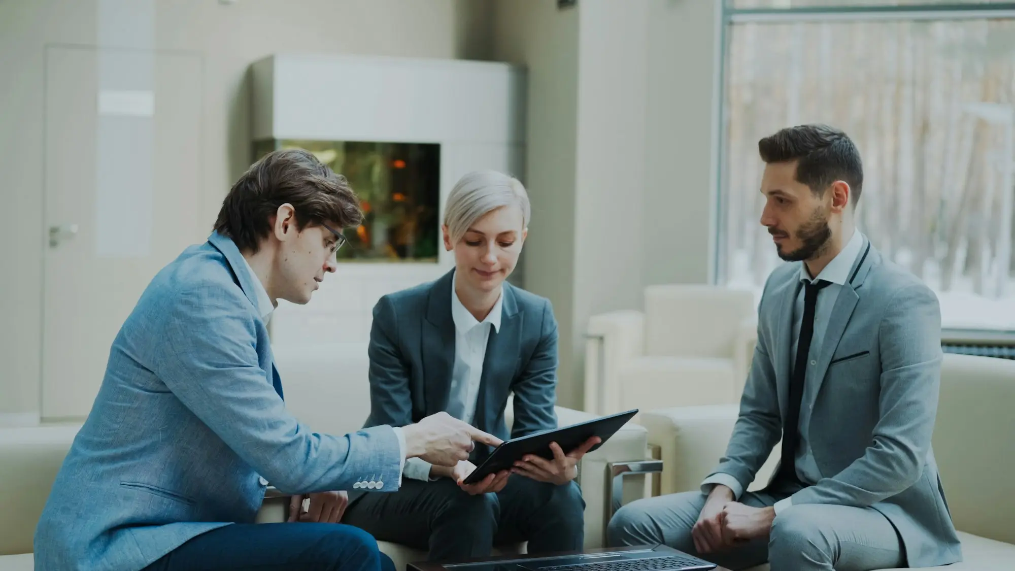 Three business partners discussing a tablet in an office