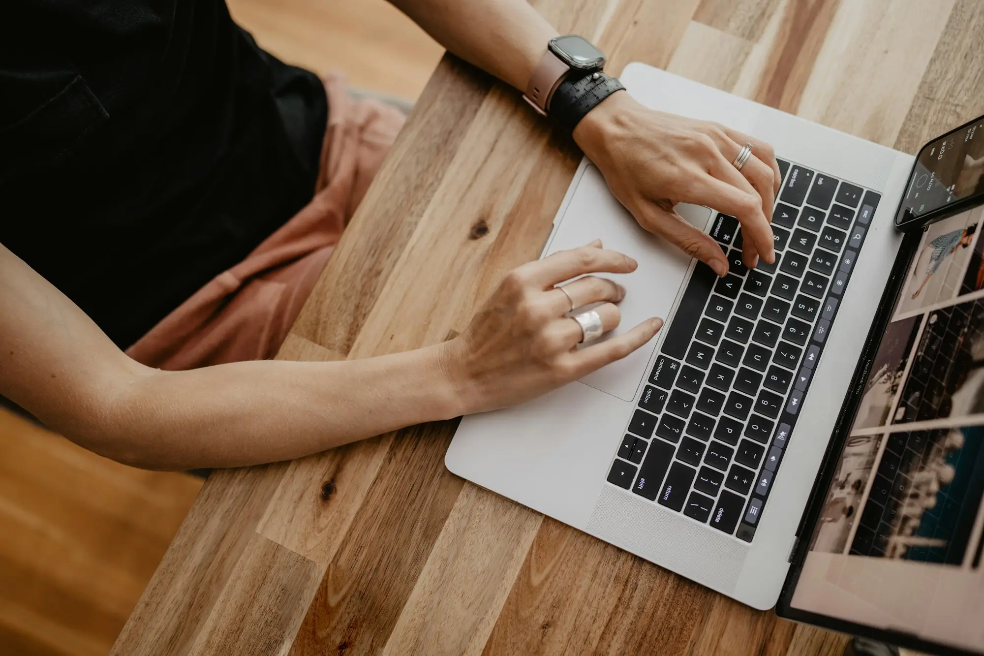 Person typing on a laptop at a wooden desk