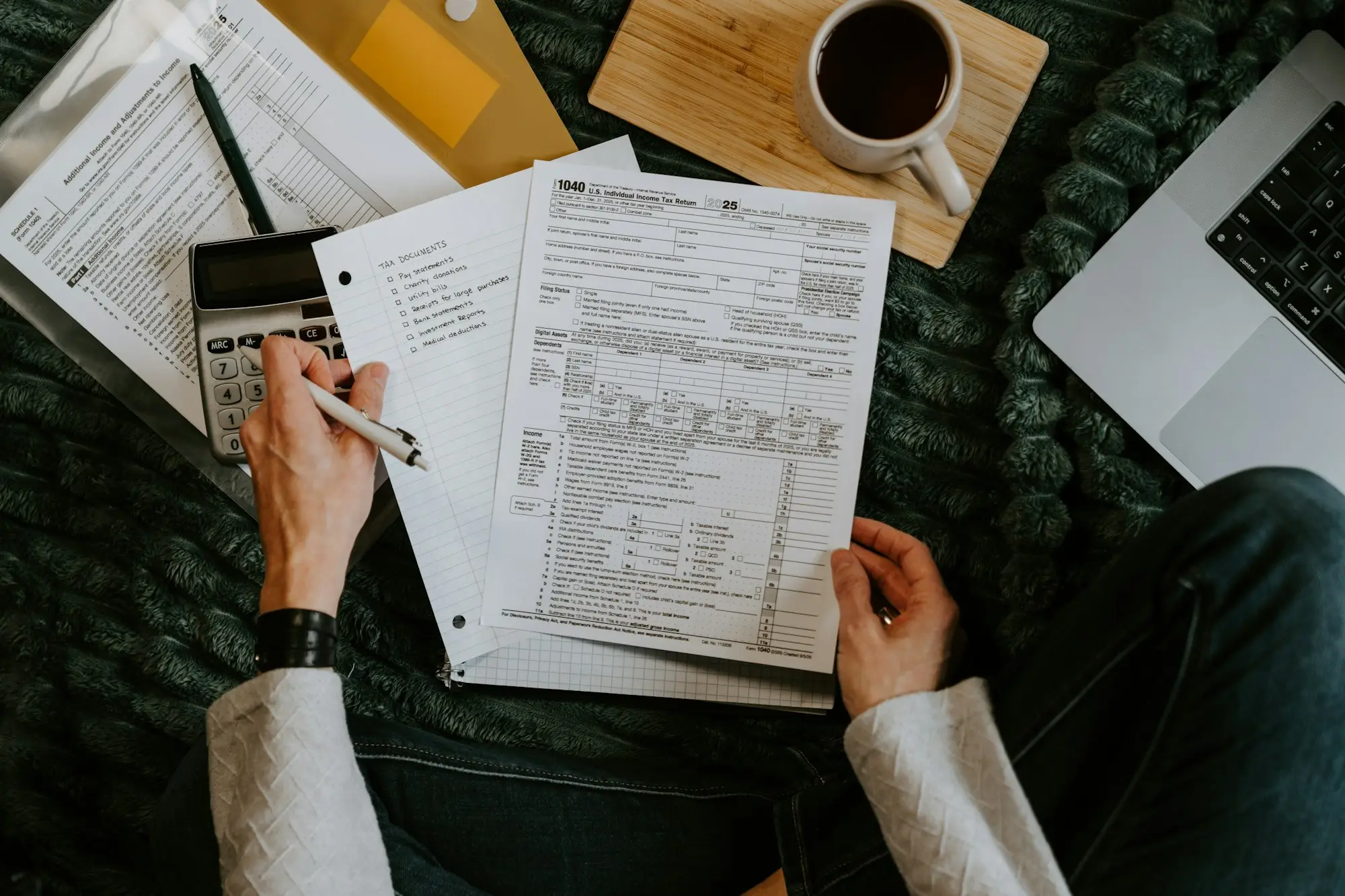 Reviewing tax documents with a calculator and laptop